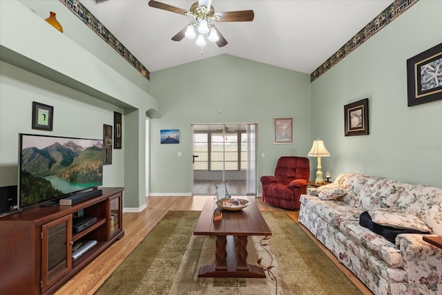 living area featuring lofted ceiling, ceiling fan, baseboards, and wood finished floors