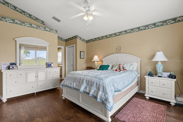 bedroom with dark wood-style flooring, lofted ceiling, a closet, visible vents, and a ceiling fan