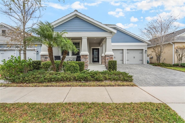 view of front of home featuring a garage, stone siding, decorative driveway, and stucco siding