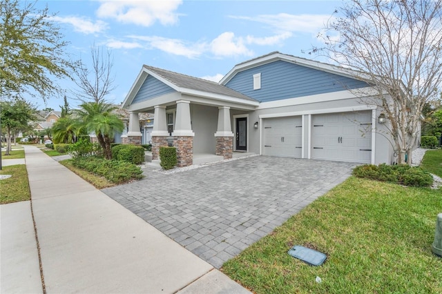 view of front of property featuring a garage, decorative driveway, stone siding, and stucco siding