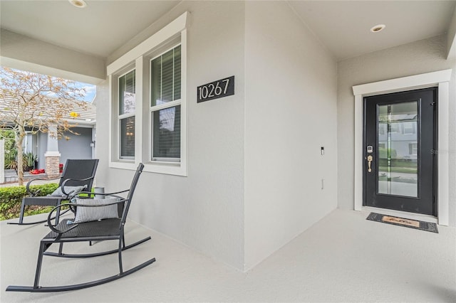 property entrance featuring covered porch and stucco siding