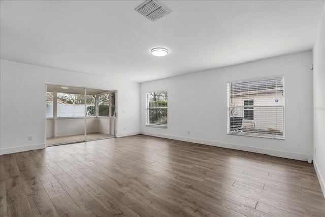 empty room featuring wood finished floors, visible vents, and baseboards