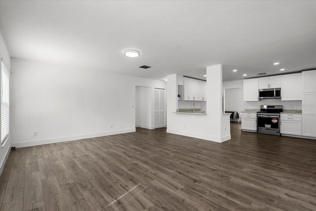 unfurnished living room featuring dark wood-type flooring, recessed lighting, and baseboards