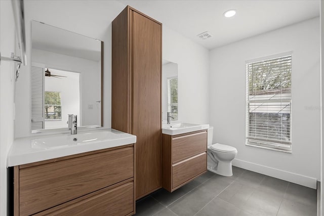 bathroom with toilet, a sink, two vanities, baseboards, and tile patterned floors