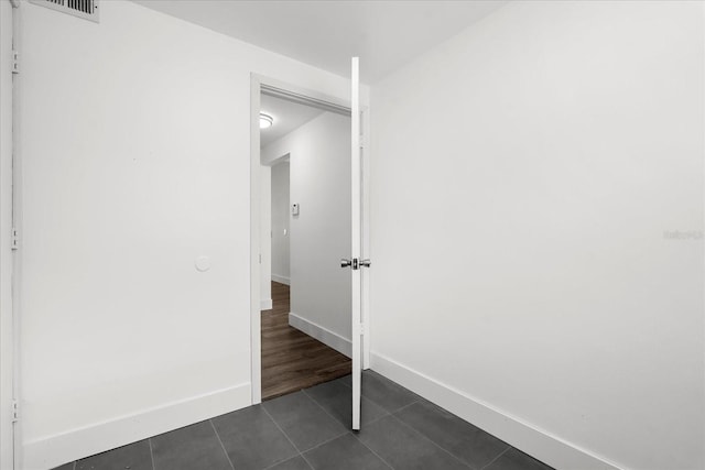 interior space with dark tile patterned flooring, visible vents, and baseboards