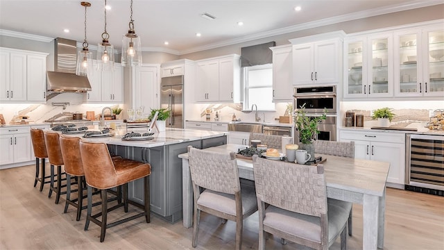 kitchen featuring beverage cooler, appliances with stainless steel finishes, a large island with sink, white cabinetry, and a sink