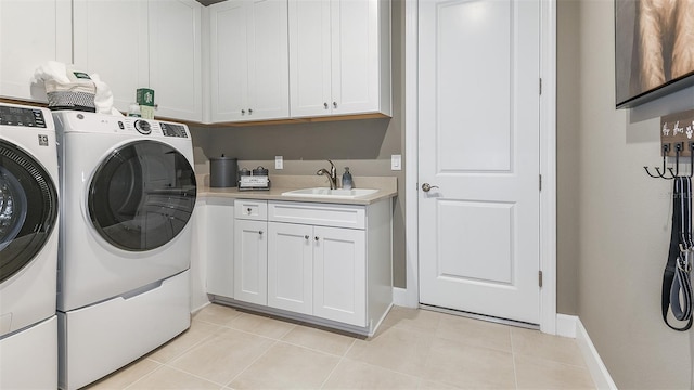 laundry area with washer and clothes dryer, light tile patterned floors, cabinet space, a sink, and baseboards