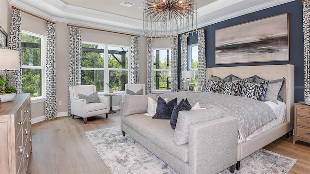 bedroom featuring ornamental molding, a tray ceiling, multiple windows, and wood finished floors