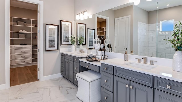 full bathroom featuring marble finish floor, baseboards, a walk in closet, and vanity