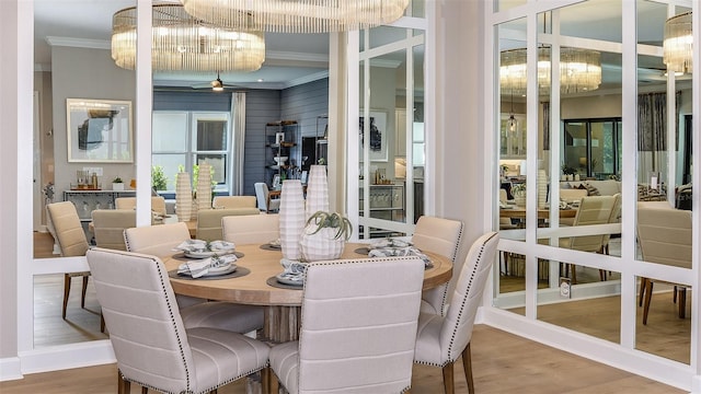 dining room featuring ceiling fan with notable chandelier, baseboards, wood finished floors, and crown molding