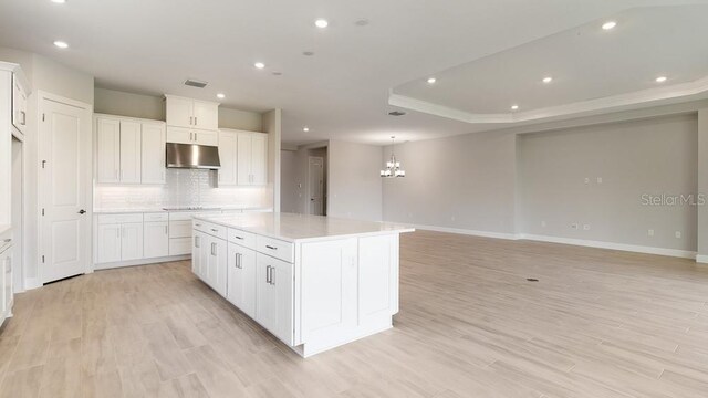 5641 Nevis Ter, Kissimmee, FL 34758 - kitchen with under cabinet range hood, a chandelier, backsplash, a kitchen island, and recessed lighting