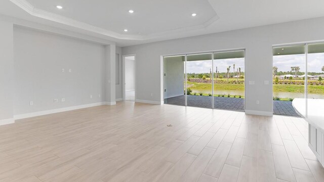 5641 Nevis Ter, Kissimmee, FL 34758 - empty room with a raised ceiling, baseboards, recessed lighting, light wood-type flooring, and ornamental molding