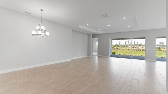 5641 Nevis Ter, Kissimmee, FL 34758 - empty room with a raised ceiling, a chandelier, healthy amount of natural light, baseboards, and recessed lighting