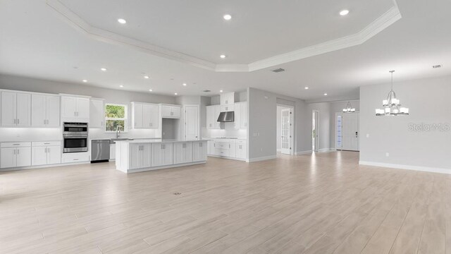 5641 Nevis Ter, Kissimmee, FL 34758 - unfurnished living room with a raised ceiling, a chandelier, ornamental molding, light wood-type flooring, and baseboards