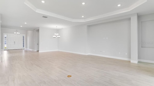 5641 Nevis Ter, Kissimmee, FL 34758 - unfurnished living room with a chandelier, a tray ceiling, crown molding, baseboards, and light wood-type flooring