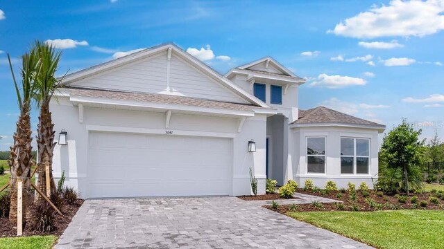 5641 Nevis Ter, Kissimmee, FL 34758 - view of front of property featuring a garage, a shingled roof, decorative driveway, and stucco siding