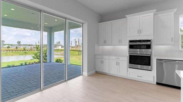 5641 Nevis Ter, Kissimmee, FL 34758 - kitchen with stainless steel appliances, a water view, light countertops, white cabinetry, and light wood-type flooring