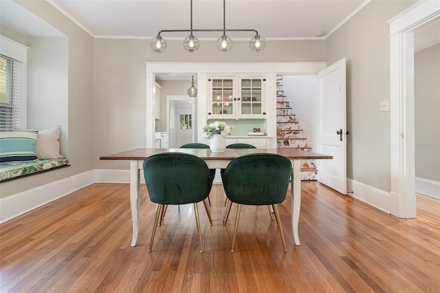 dining space featuring crown molding, baseboards, and light wood finished floors