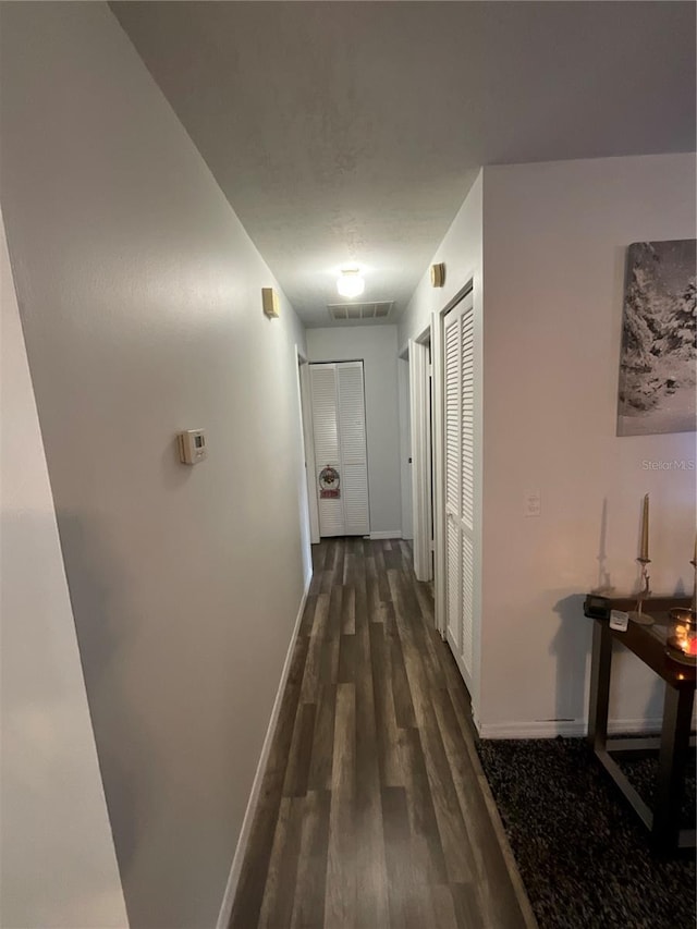 corridor with visible vents, dark wood finished floors, and baseboards