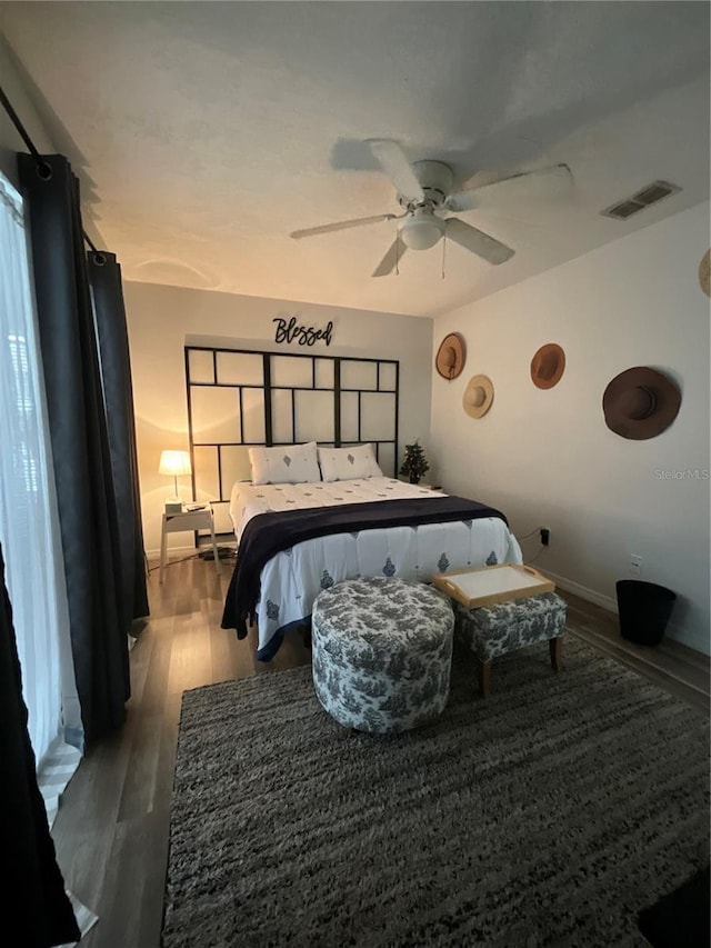 bedroom with a ceiling fan, baseboards, visible vents, and wood finished floors