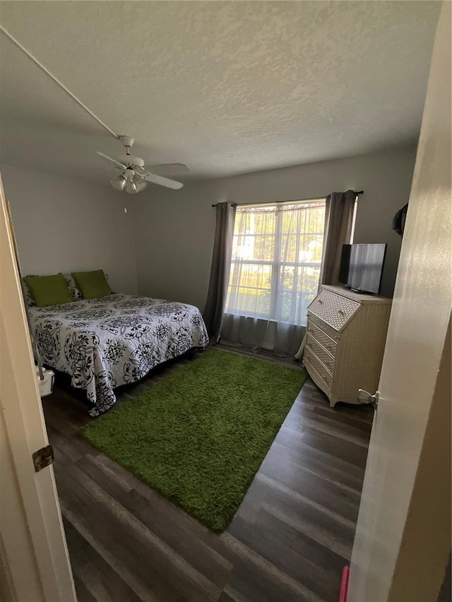 bedroom with a textured ceiling, ceiling fan, and wood finished floors