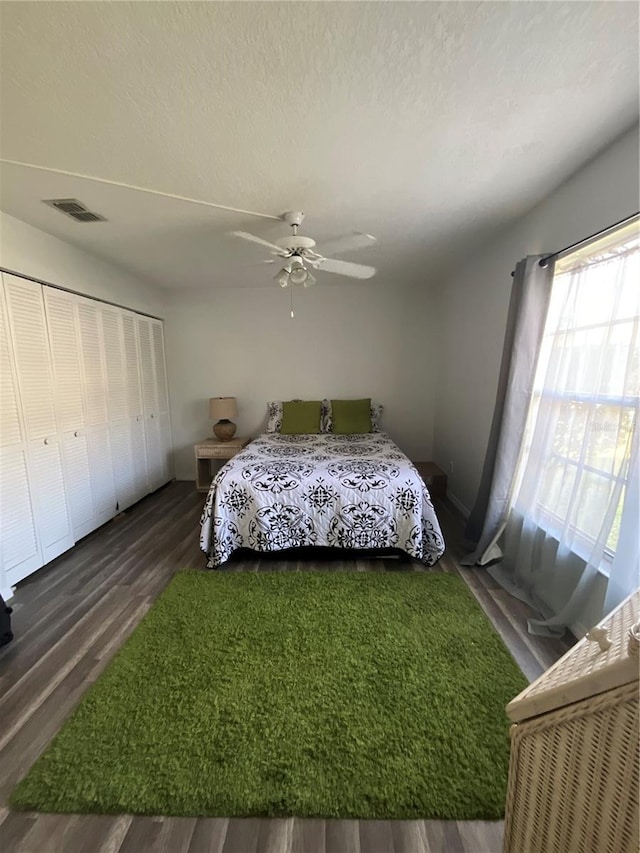 bedroom with a closet, visible vents, a ceiling fan, a textured ceiling, and wood finished floors