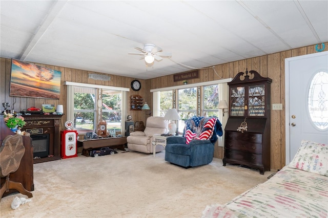 interior space featuring wood walls, a ceiling fan, and a glass covered fireplace