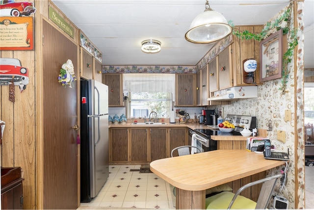 kitchen featuring light countertops, appliances with stainless steel finishes, a sink, under cabinet range hood, and wallpapered walls