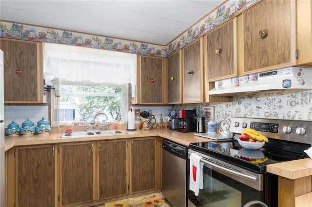 kitchen featuring under cabinet range hood, appliances with stainless steel finishes, light countertops, and a sink