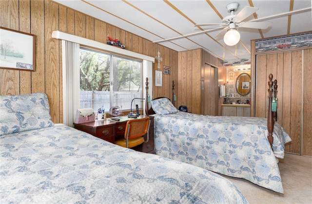 bedroom with carpet flooring, a ceiling fan, and wooden walls