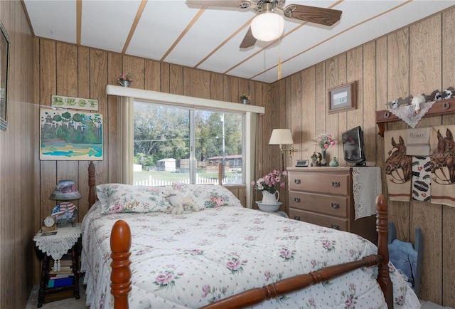 bedroom featuring ceiling fan and wooden walls