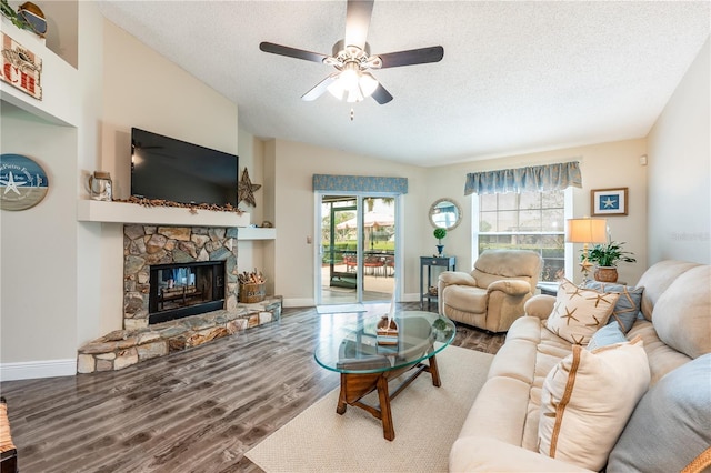 living area with a textured ceiling, a fireplace, wood finished floors, baseboards, and vaulted ceiling