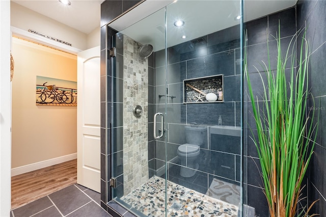 bathroom featuring a stall shower, wood finished floors, toilet, and baseboards