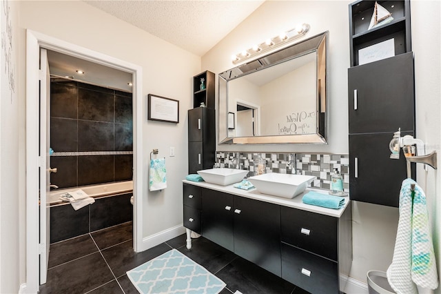 full bath with tile patterned flooring, a textured ceiling, backsplash, and a sink