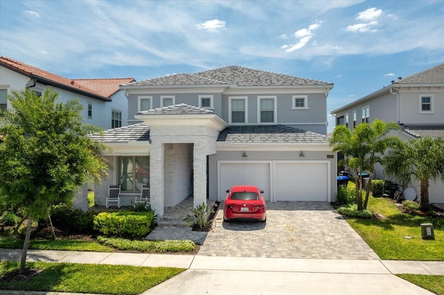 view of front of home with decorative driveway, an attached garage, and stucco siding