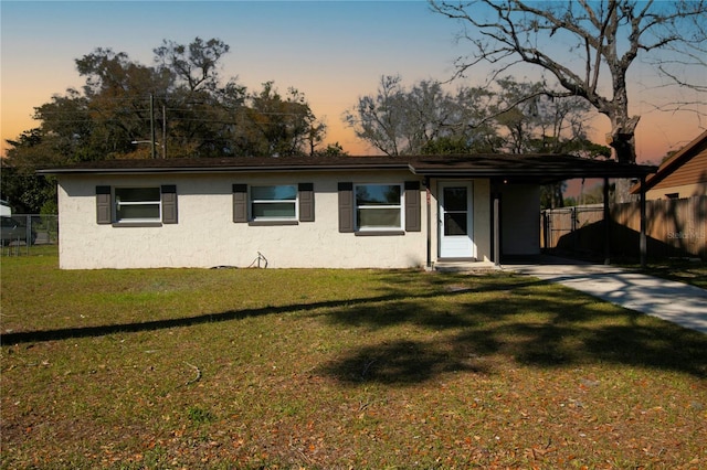 ranch-style house featuring a lawn, fence, and stucco siding