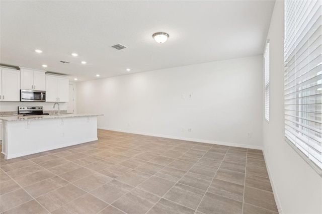4365 Switchgrass Ln, Saint Cloud, FL 34772 - kitchen with light stone countertops, a kitchen bar, recessed lighting, appliances with stainless steel finishes, and baseboards