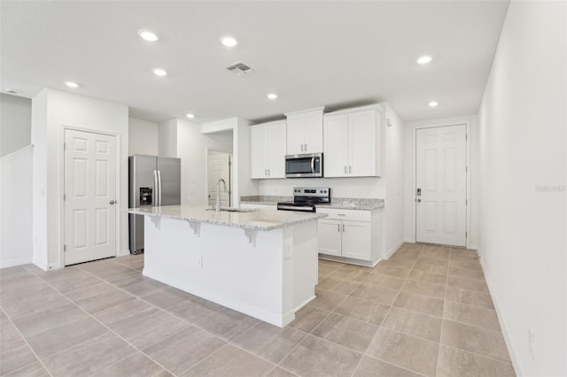 4365 Switchgrass Ln, Saint Cloud, FL 34772 - kitchen featuring white cabinets, a sink, appliances with stainless steel finishes, an island with sink, and a breakfast bar area