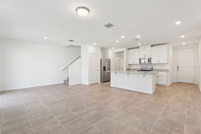 4365 Switchgrass Ln, Saint Cloud, FL 34772 - kitchen featuring visible vents, open floor plan, an island with sink, a kitchen breakfast bar, and stainless steel appliances