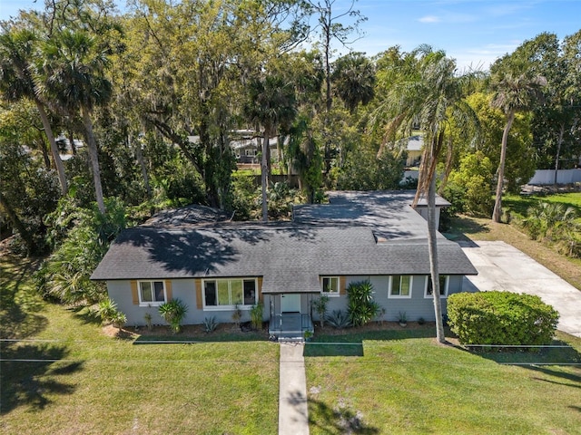 view of front of house with a front lawn, driveway, and roof with shingles