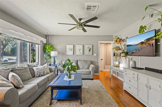 living area with visible vents, a ceiling fan, dark wood-style flooring, and a textured ceiling