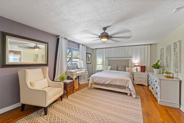 bedroom featuring a textured ceiling, wood finished floors, baseboards, and ceiling fan