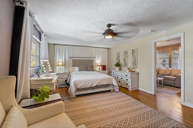 bedroom featuring baseboards, a textured ceiling, wood finished floors, and a ceiling fan