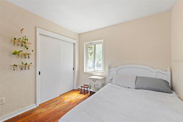 bedroom with wood finished floors, a closet, and a textured wall