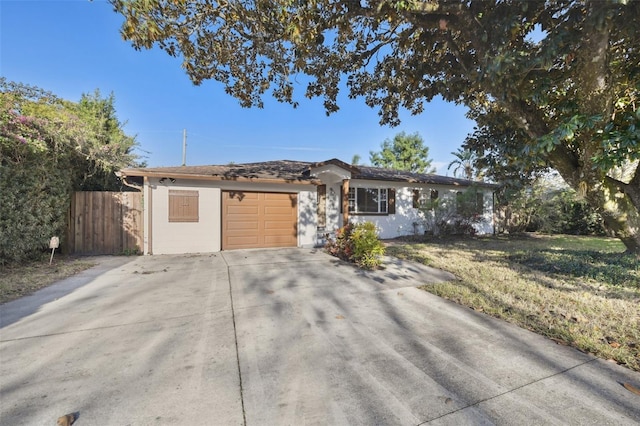 single story home featuring a garage, concrete driveway, and fence