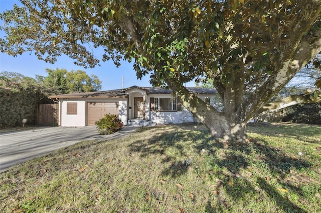 ranch-style house with a front yard, driveway, an attached garage, and stucco siding