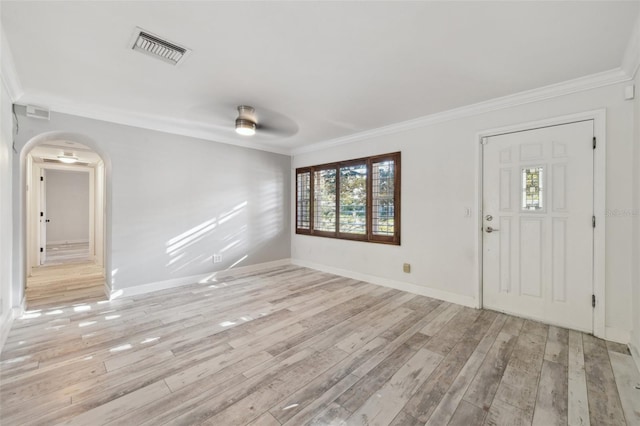 entrance foyer featuring arched walkways, ornamental molding, visible vents, and light wood-style floors