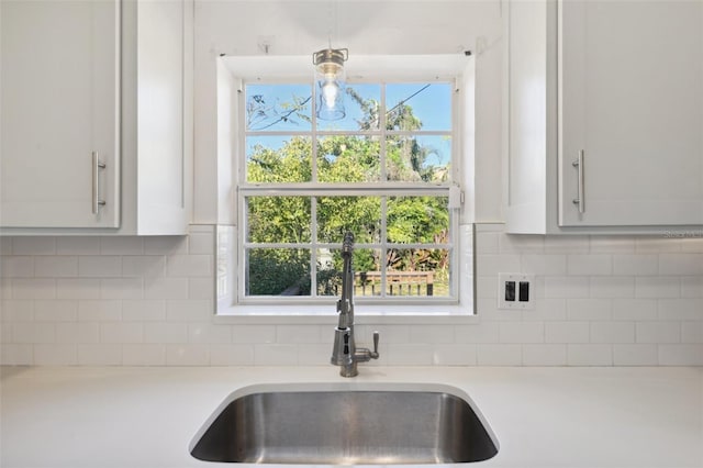 kitchen featuring light countertops, tasteful backsplash, a sink, and white cabinets