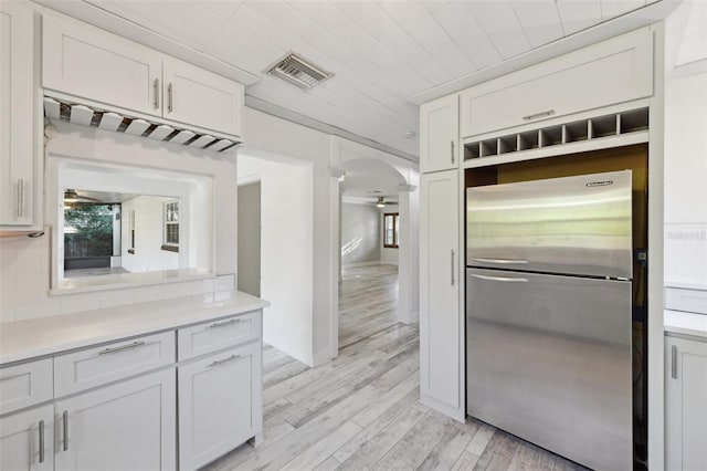 kitchen with visible vents, arched walkways, freestanding refrigerator, light countertops, and light wood-style floors