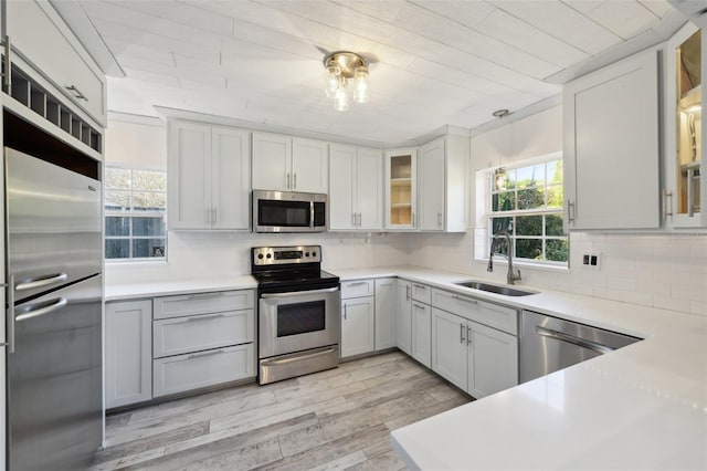 kitchen with appliances with stainless steel finishes, a wealth of natural light, a sink, and decorative backsplash